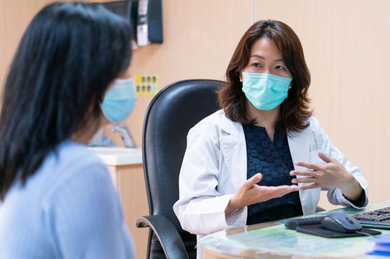A doctor and patient during an office visit wearing masks.