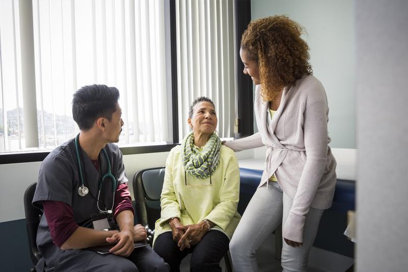 An African American daughter consoles her mother upon hearing medical news from the nurse.