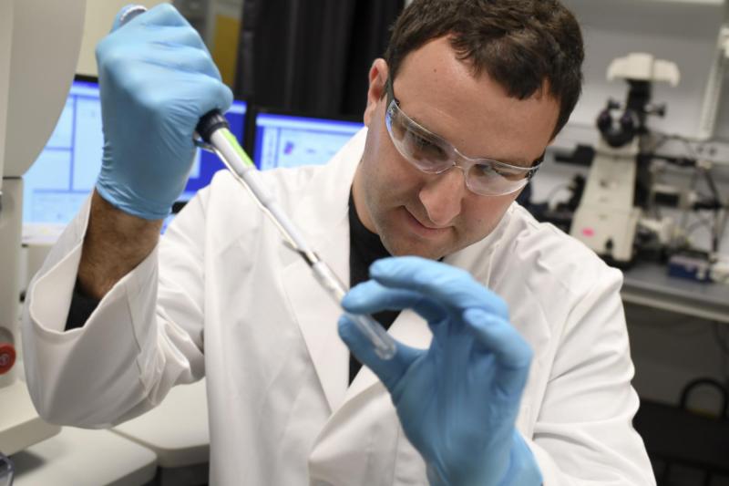 A male researcher examines a test tube in the hospital lab.