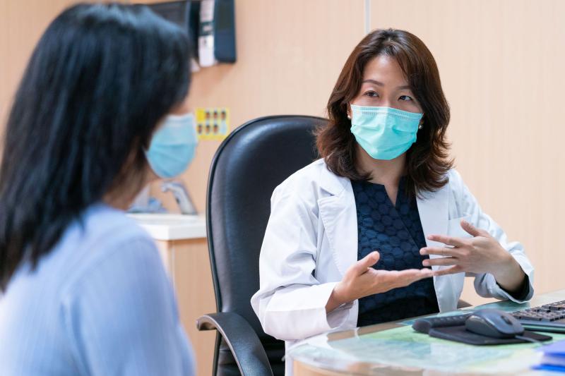 A doctor and patient during an office visit wearing masks.