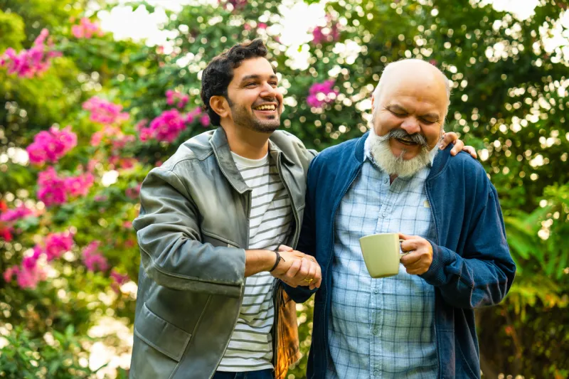 Senior father and son bonding over coffee while walking in the garden