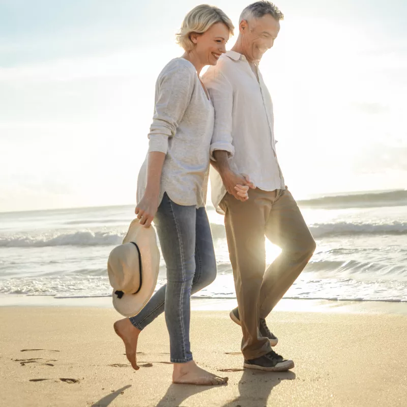 A couple walks on the beach near sunset.