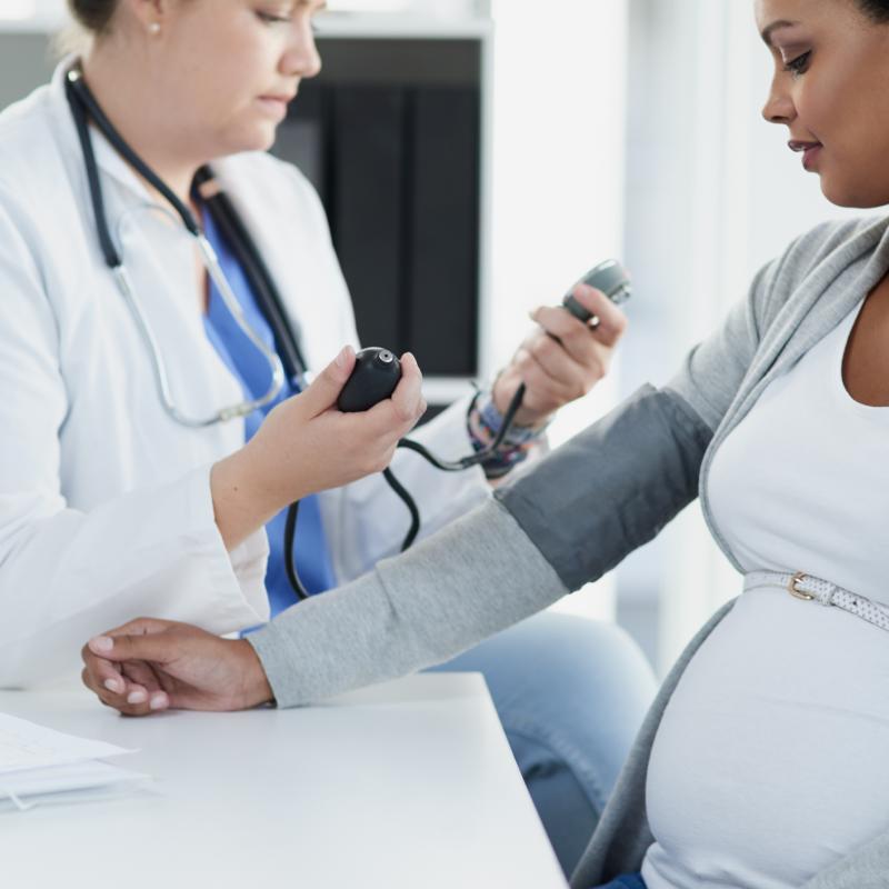 One pregnant woman getting her blood checked by a female doctor in scrubs.